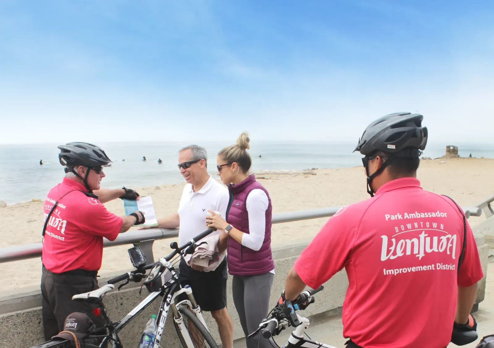 Park Safety Ambassadors on bikes talking with two visitors at the beach
